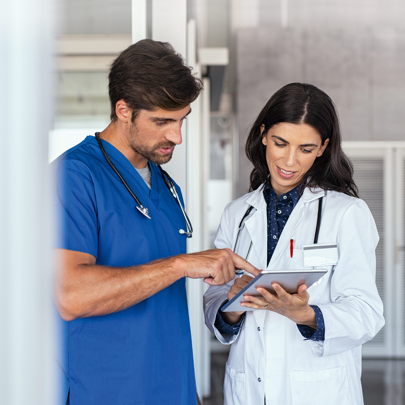 Zwei Mitarbeiter in einem Krankenhaus gehen Behandlungspläne auf einem Tablet durch.
